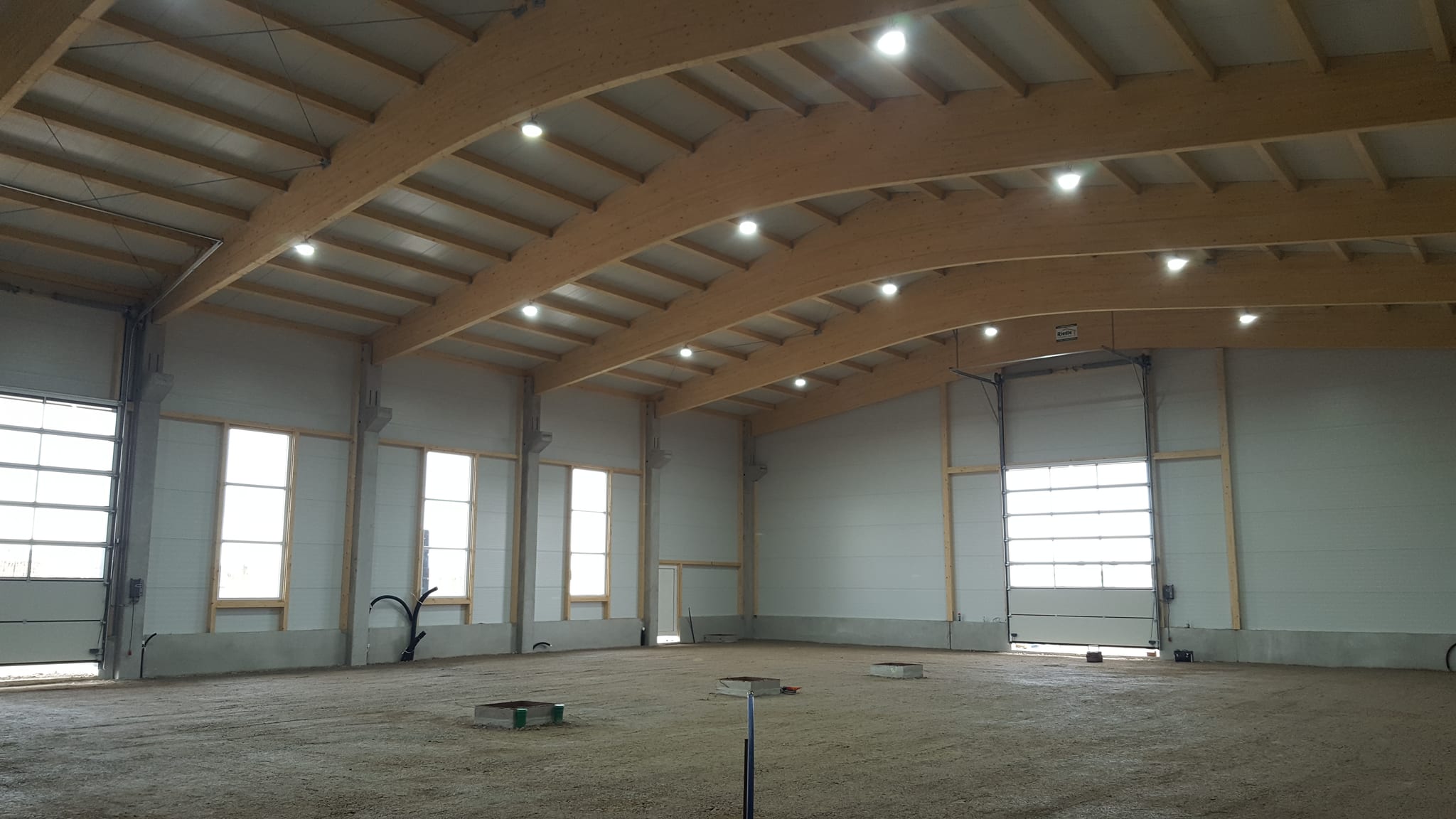 3. März 2017, zum ersten Mal Licht in der Halle: die Leuchten brennen unter den Bindern aus Brettschichtholz, der Boden ist noch Schotter