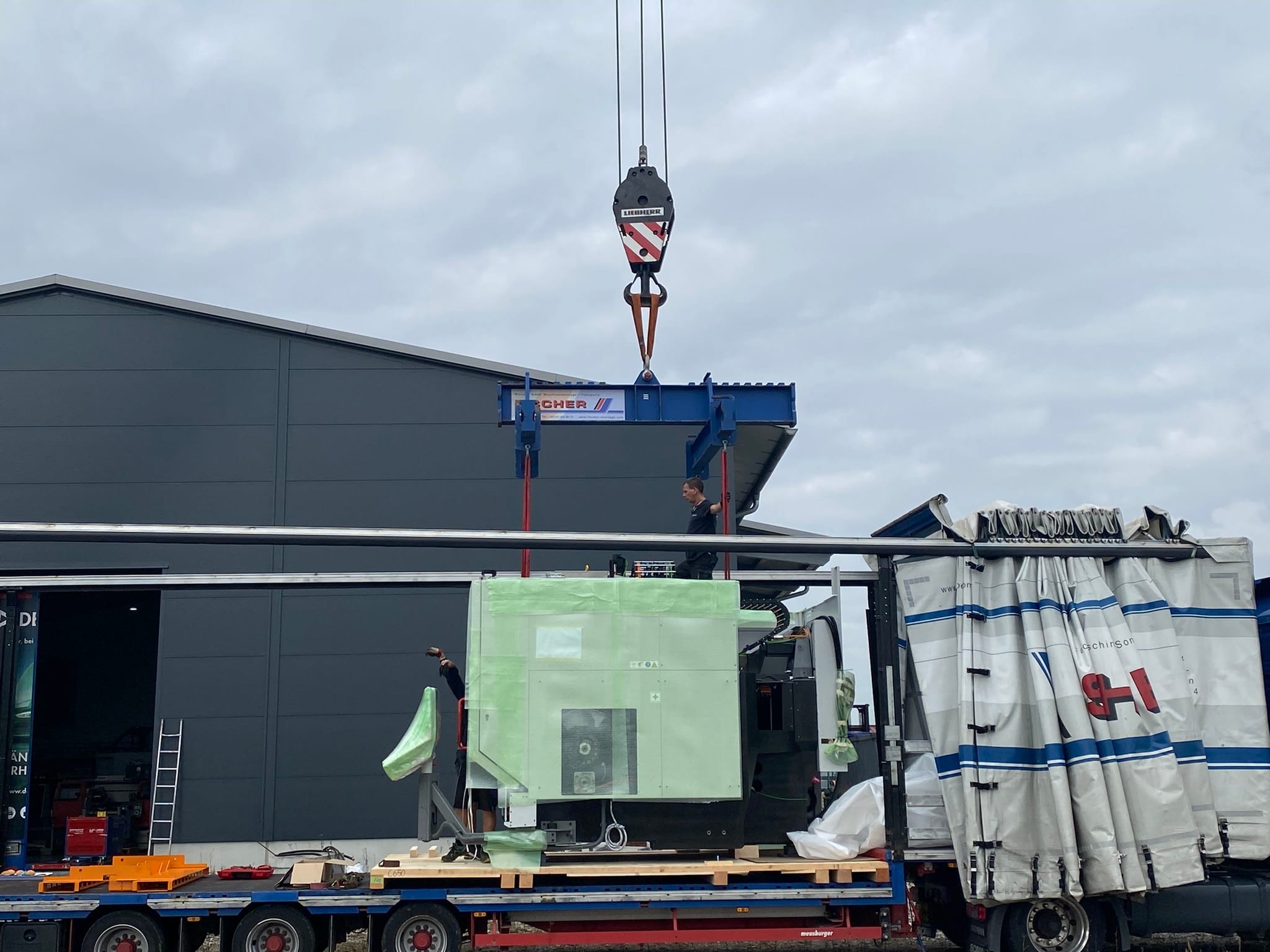 Die C650U in grüner Schutzfolie auf der Ladefläche, darüber die Traverse am Kranhaken