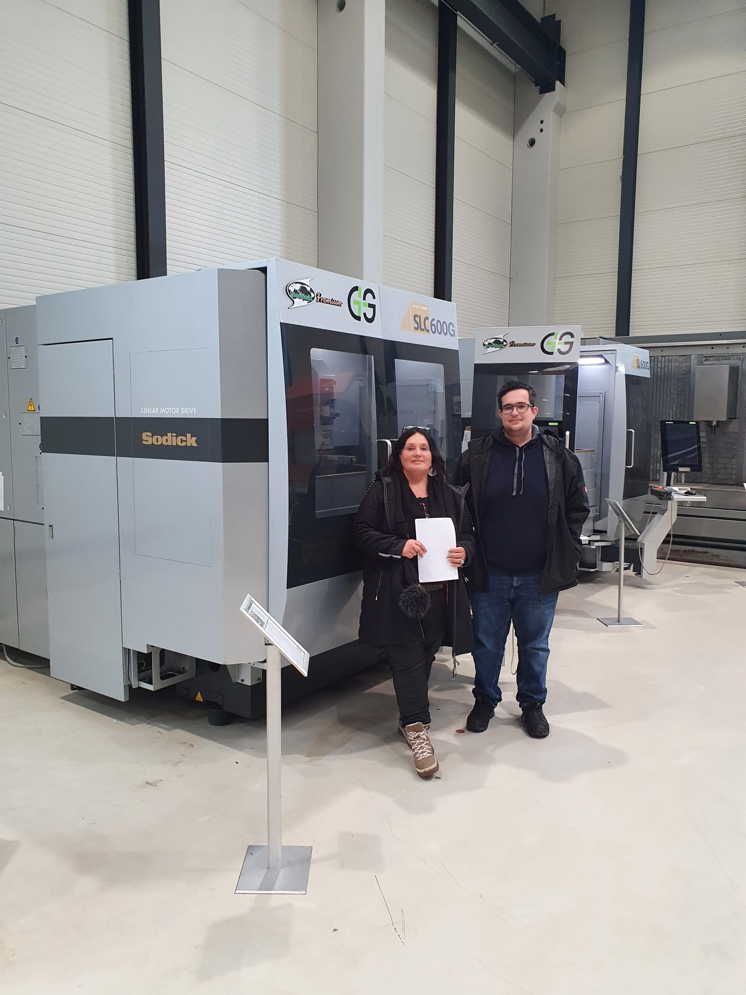 Zwei Personen vor der neuen Sodick SLC600G im Vorführraum: auf der Haube der Schriftzug SLC600G, links am Gehäuse der Schriftzug Linear Motor Drive, dahinter eine zweite Anlage derselben Baureihe