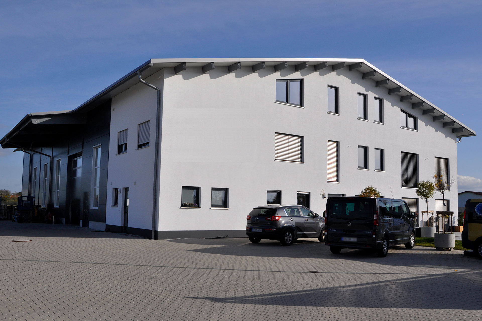 Firmengebäude in der Gutenbergstraße: helle Halle mit Bürotrakt, Karl-Logo an der Giebelwand, Stellplätze im Hof